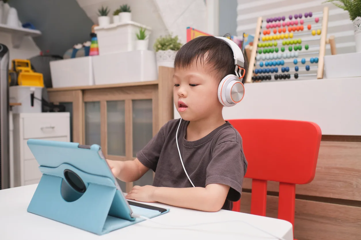 A young boy using a tablet at home to follow an online lesson