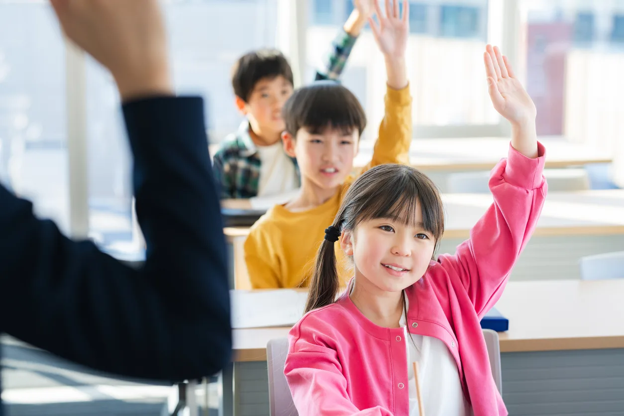 Elementary school students raising their hands to answer