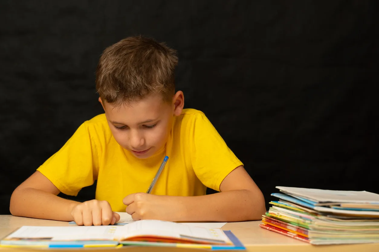Schoolboy solves homework sitting at the table
