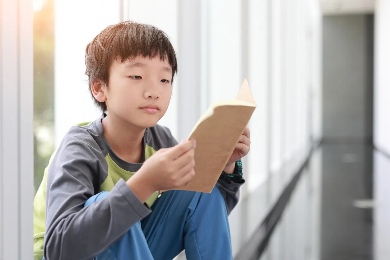 Cute boy reading book in library